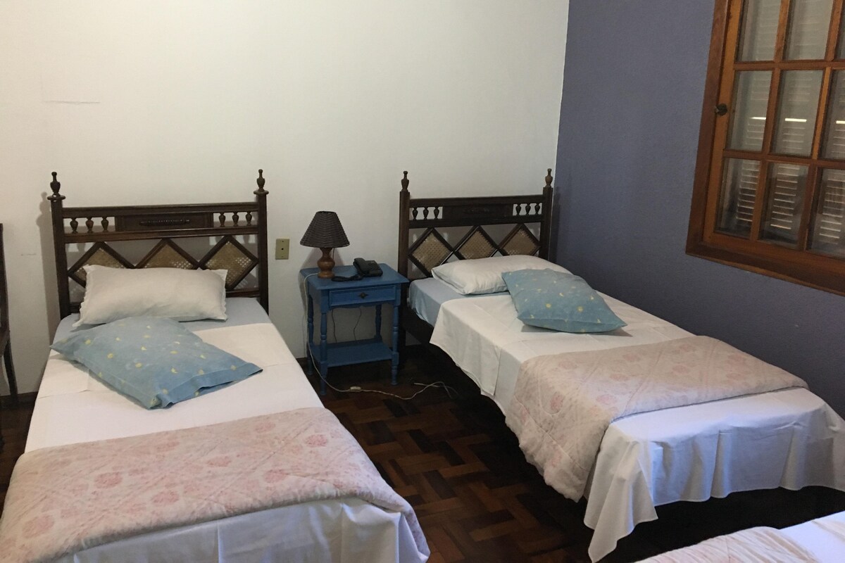 Una habitación con dos camas individuales, cada una con cabecero de madera y una mesita de noche con lámpara.