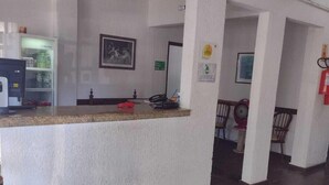 A reception area with a counter, a refrigerator, a fire extinguisher, and a framed picture on the wall. - Roma Hotel (Porto Alegre)