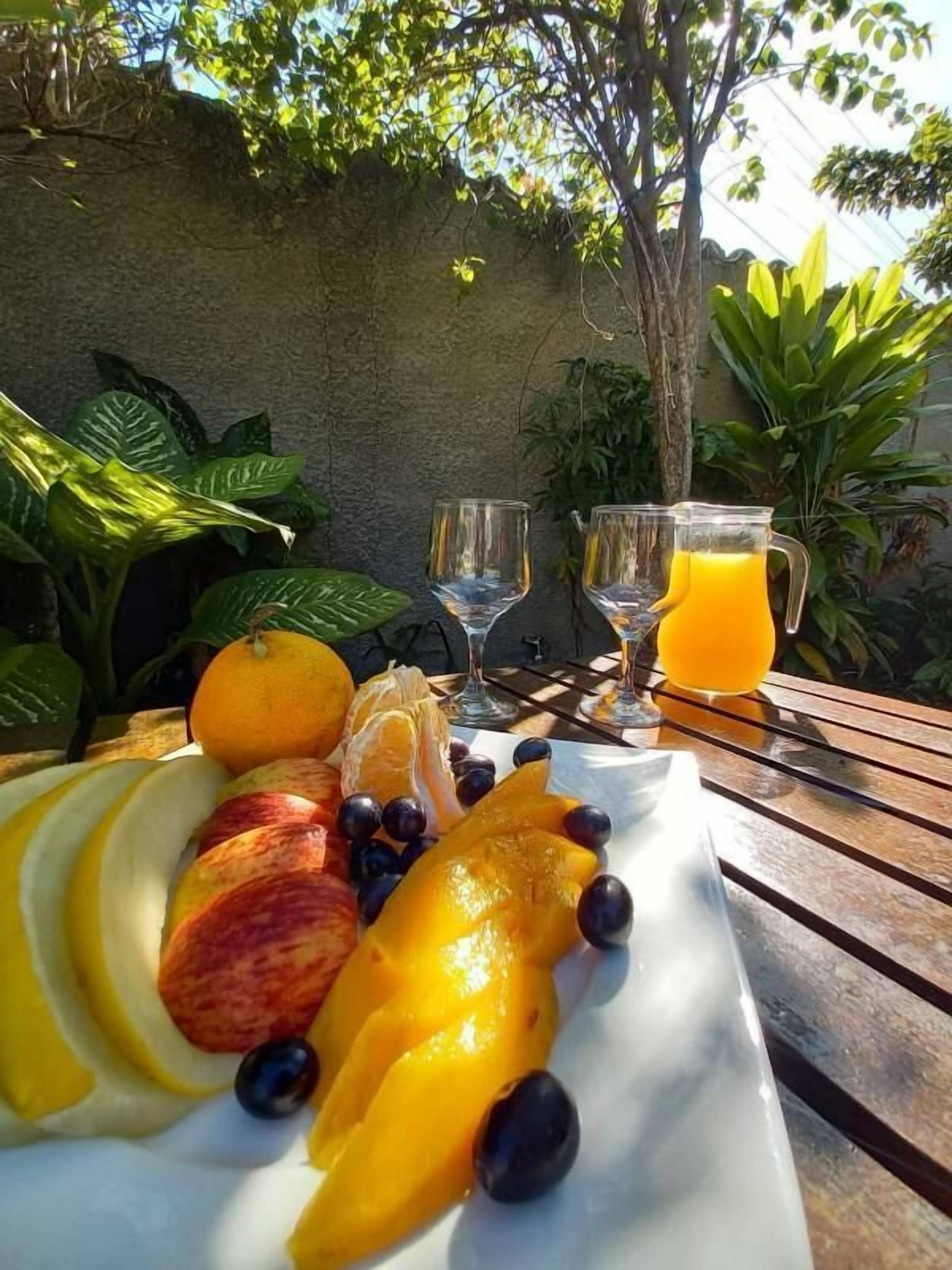 Una mesa con una bandeja de fruta, dos vasos y una jarra de jugo de naranja.