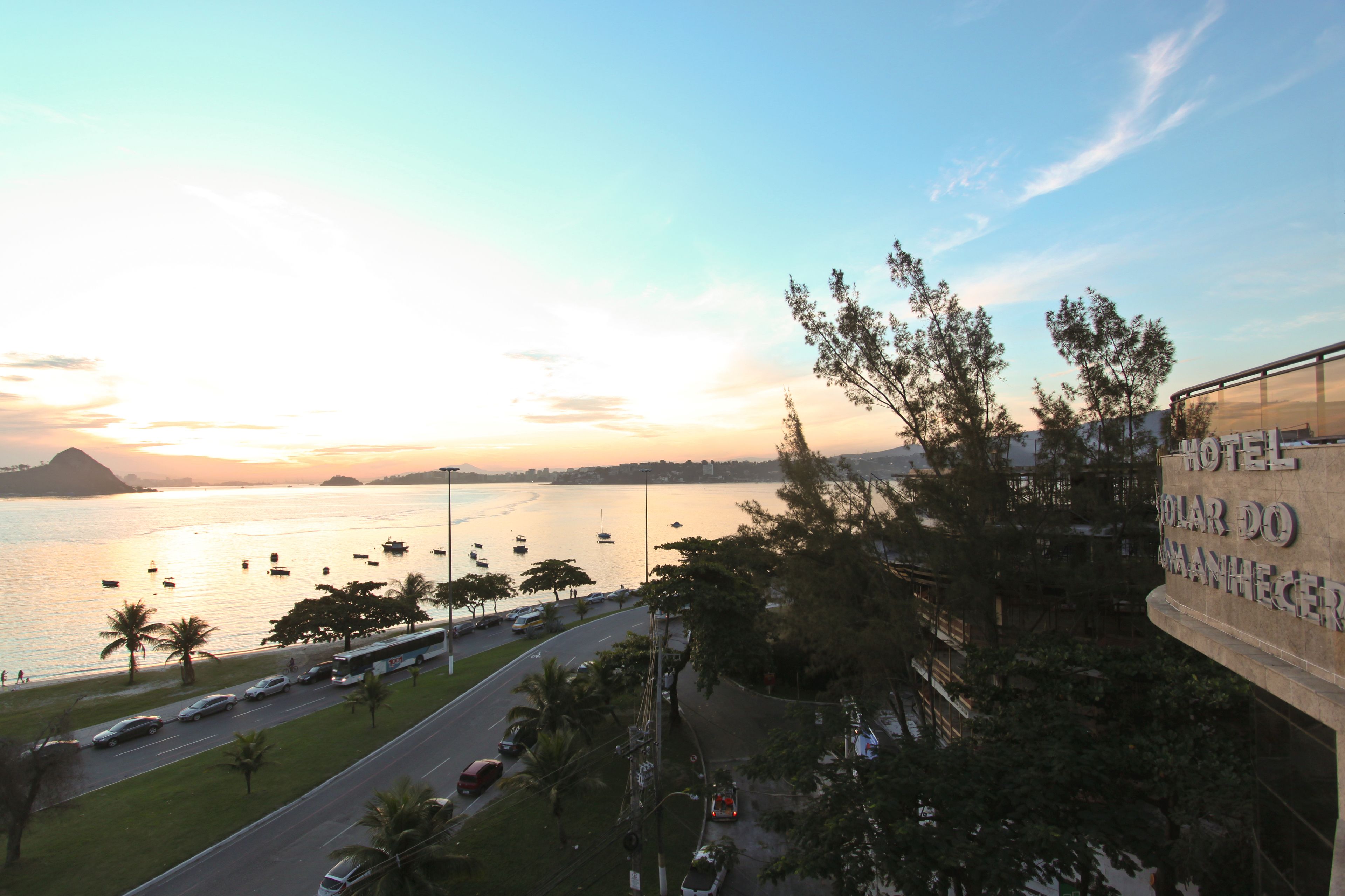 A view of the ocean with boats, a road with cars, and a building with a sign that reads "HOTEL SOLAR DO ARANHECER".