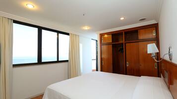 A hotel room with a large bed, a wardrobe, a window with curtains, and a ceiling light.