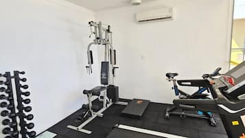 Ein Fitnessraum mit Laufband, Gewichte-Bank und Squat-Rack.