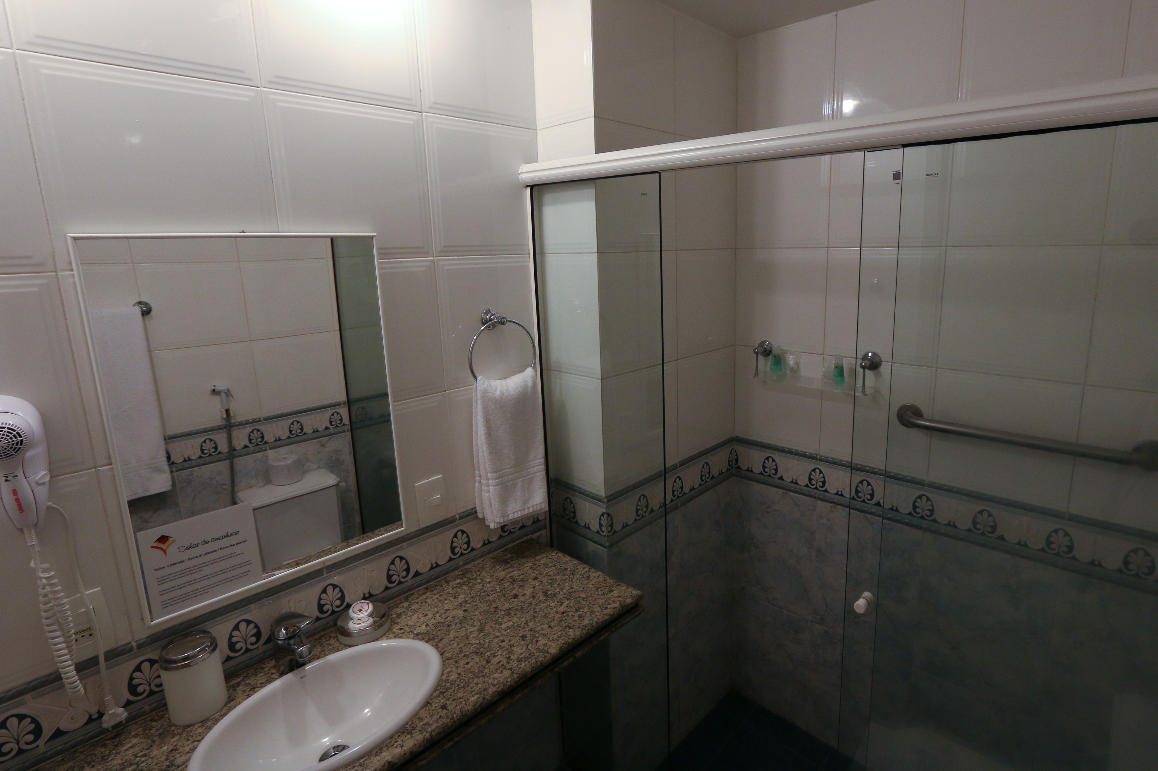A bathroom with a sink, mirror, towel rack, and a glass shower enclosure.