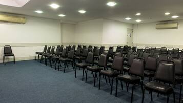 A conference room with rows of black chairs, a blue carpet, and recessed ceiling lights.