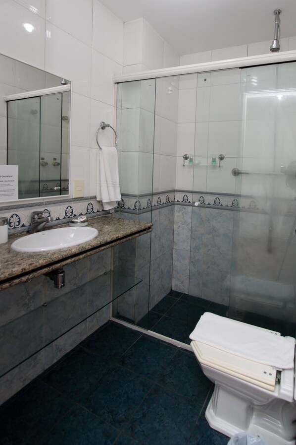 Un baño con lavamanos, espejo, inodoro y ducha.