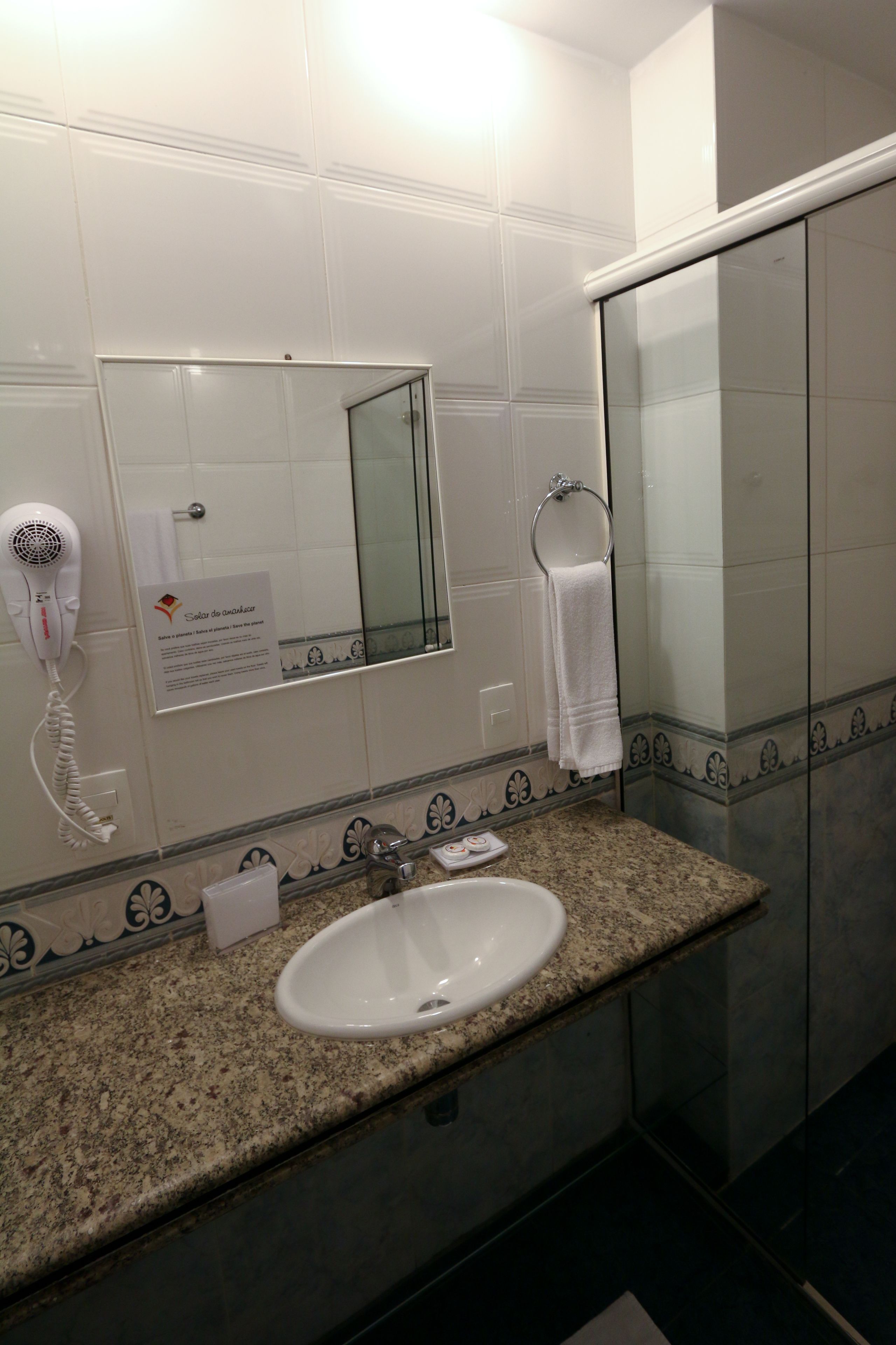 Un baño con lavabo, espejo, toallero y secador de pelo.