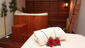 A spa room with a wooden bench, a hot tub, and a towel with roses. - Solar do Amanhecer (Niteroi)