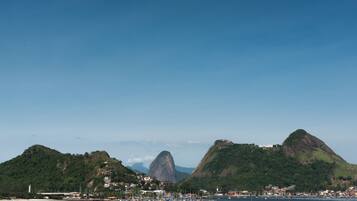 A coastal town with a prominent mountain, a marina with boats, and buildings along the shore.