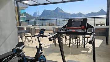 Een sportschool met trainingsapparatuur en uitzicht op bergen.