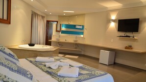 Une chambre d’hôtel avec un grand lit, une baignoire, un meuble-lavabo avec deux vasques, un téléviseur à écran plat et un petit réfrigérateur.