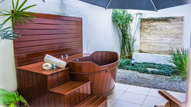 Un espace de détente avec un banc en bois, un jacuzzi et un sol carrelé.