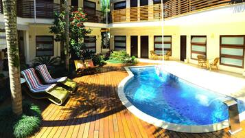 Una piscina al aire libre, sillones reclinables de piscina