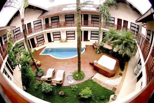 A multi-level outdoor area with a swimming pool, lounge chairs, a hot tub, and various plants.