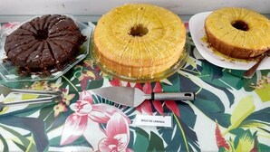 Three cakes on a table with a floral tablecloth. - Pousada Da Bia (RIO DAS OSTRAS)