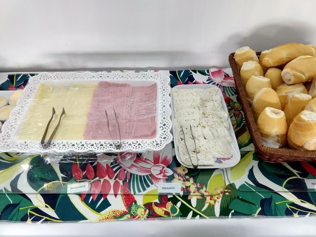 Una mesa con comida, incluyendo carnes en rodajas y pan, sobre un mantel colorido.