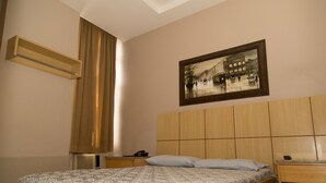 A bedroom with a bed, a headboard, a nightstand, a telephone, and a painting on the wall. - Hotel Puma (Rio de Janeiro)
