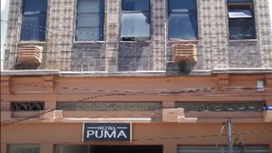 A multi-story building with a patterned facade, a sign for 'PUMA' hotel, and a gated entrance. - Hotel Puma (Rio de Janeiro)
