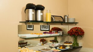A buffet with various food items and beverages, including coffee and tea dispensers, and a vase of flowers. - Hotel Puma (Rio de Janeiro)