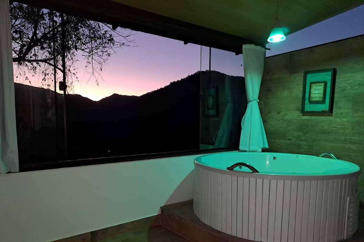 Ein modernes Badezimmer mit einer großen Badewanne, Blick auf die Berge bei Sonnenuntergang und einem gerahmten Zitat an der Wand.