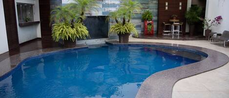 Una piscina al aire libre, sillones reclinables de piscina