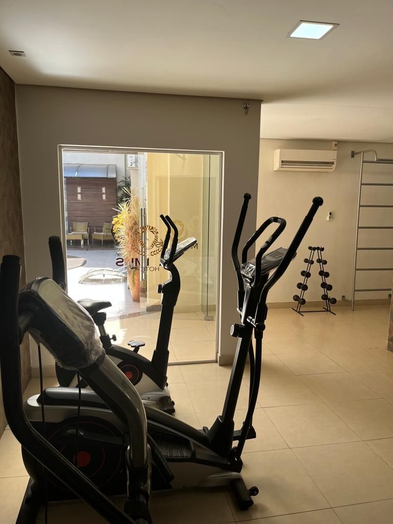 Un gimnasio en casa con dos máquinas elípticas, un juego de mancuernas y una puerta que da a un patio con mobiliario exterior.