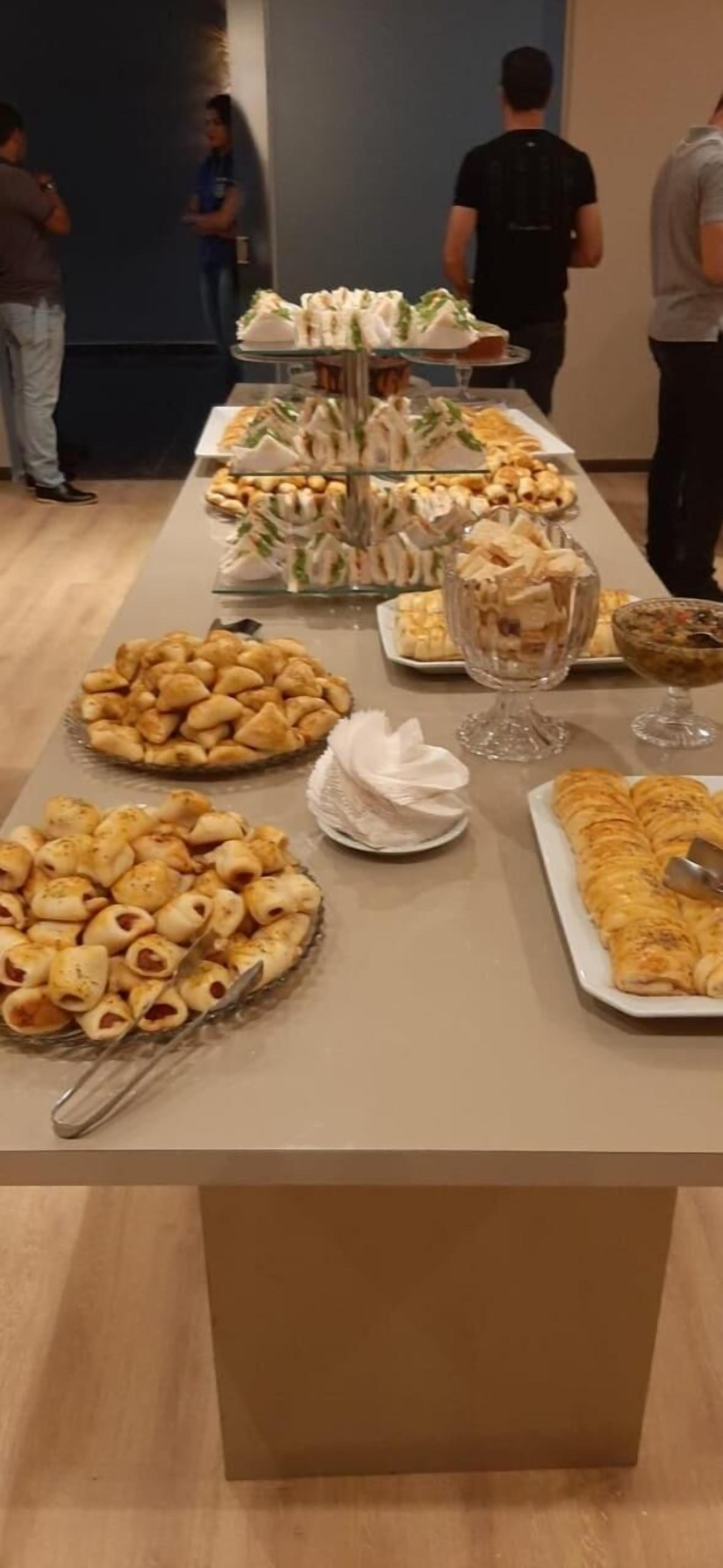 A buffet table with various food items including pastries, sandwiches, and desserts.