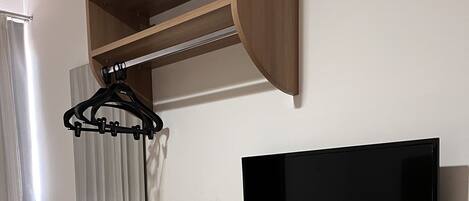 A compact living space with a wooden desk, a flat-screen TV, and a compact refrigerator.