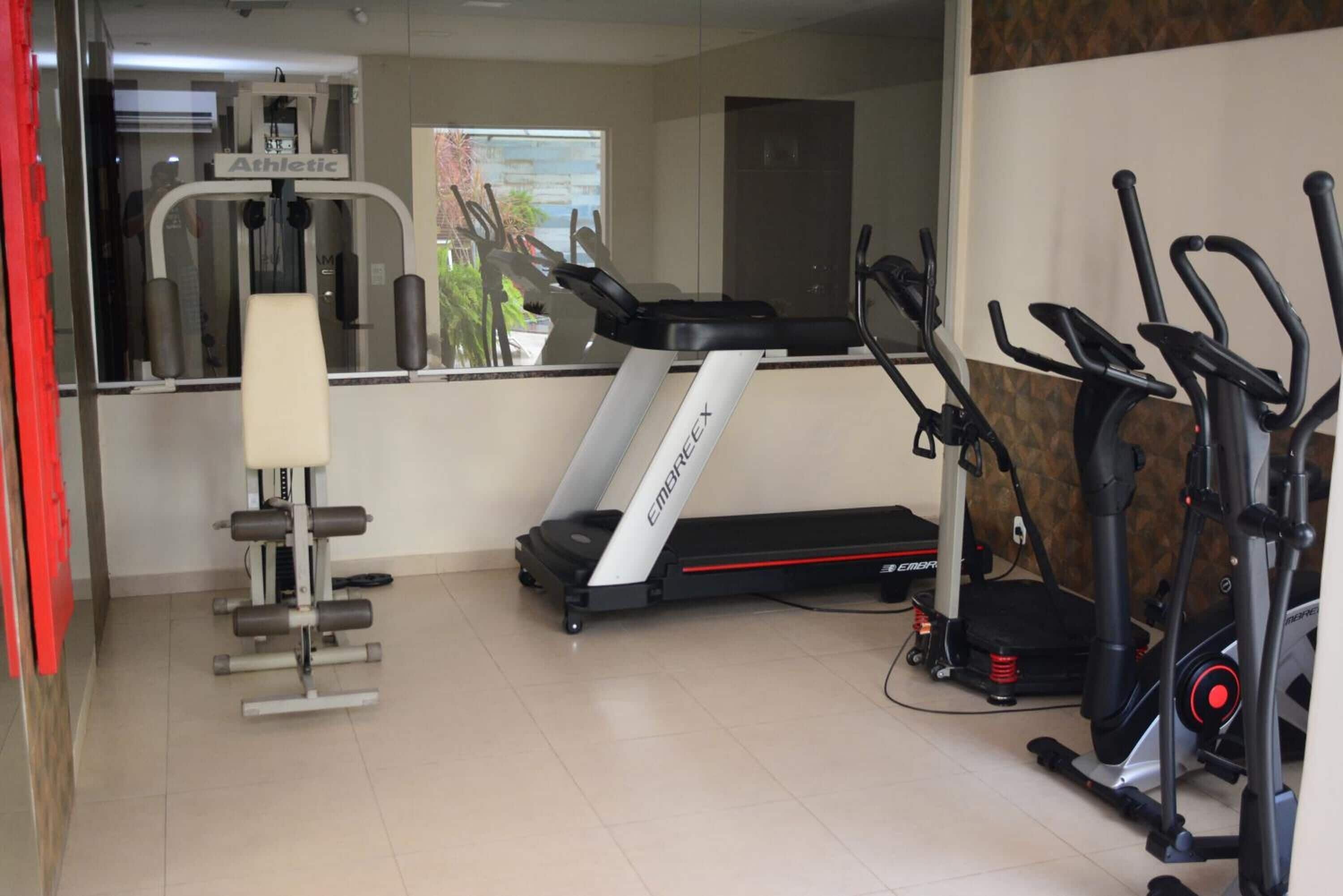 Een fitnessruimte met loopband, elliptische trainer en krachtapparaat.