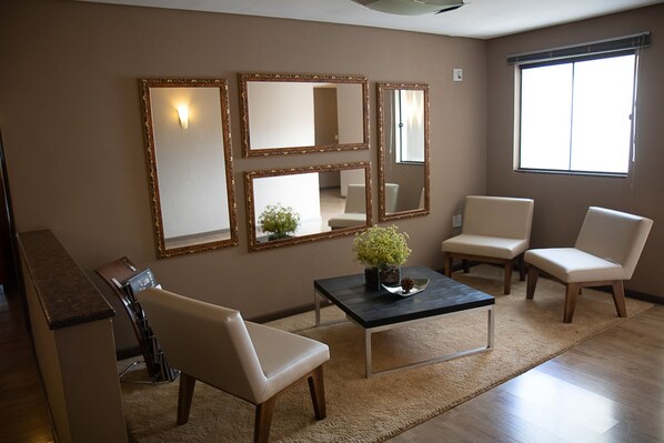 A living room with a sofa, two armchairs, a coffee table, and three wall-mounted mirrors.