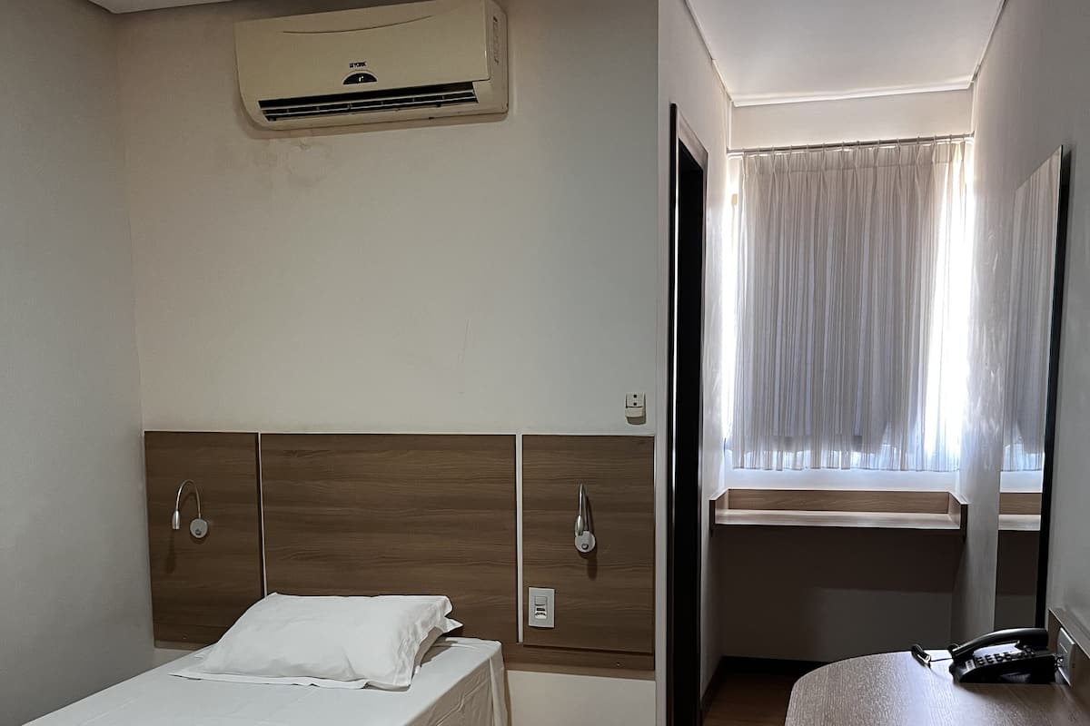 Une chambre d’hôtel avec un lit, un bureau et une fenêtre avec des rideaux.