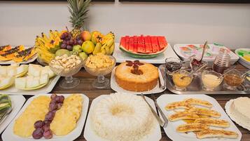 A buffet with various fruits, desserts, and beverages.