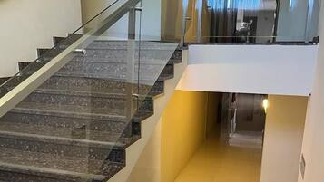 A modern interior with a glass railing staircase leading to a second floor.