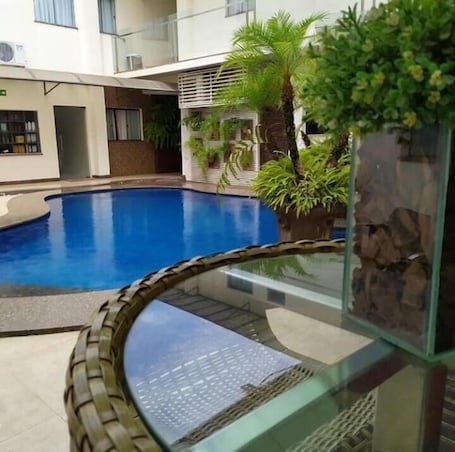 Una piscina al aire libre, sillones reclinables de piscina