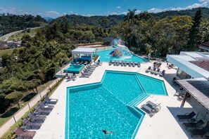 A large swimming pool with a water slide, surrounded by lounge chairs and a covered area. - Monthez Hotel & Eventos (Brusque)