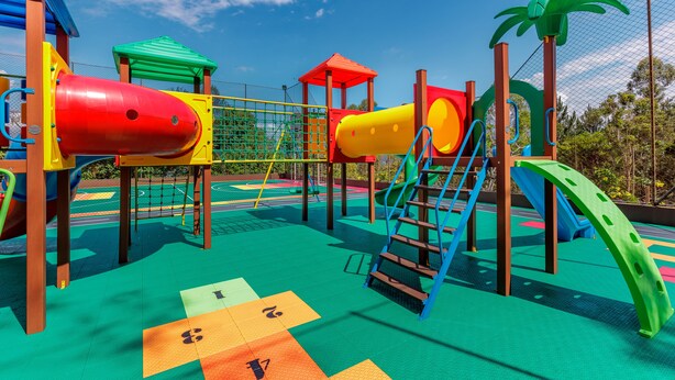 Un parque infantil con estructuras de juego coloridas y una red de escalada verde.