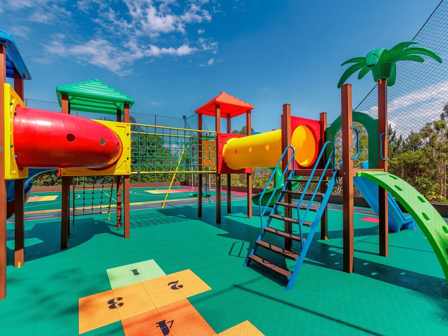 Un parque infantil con estructuras de juego coloridas y una red de escalada verde.
