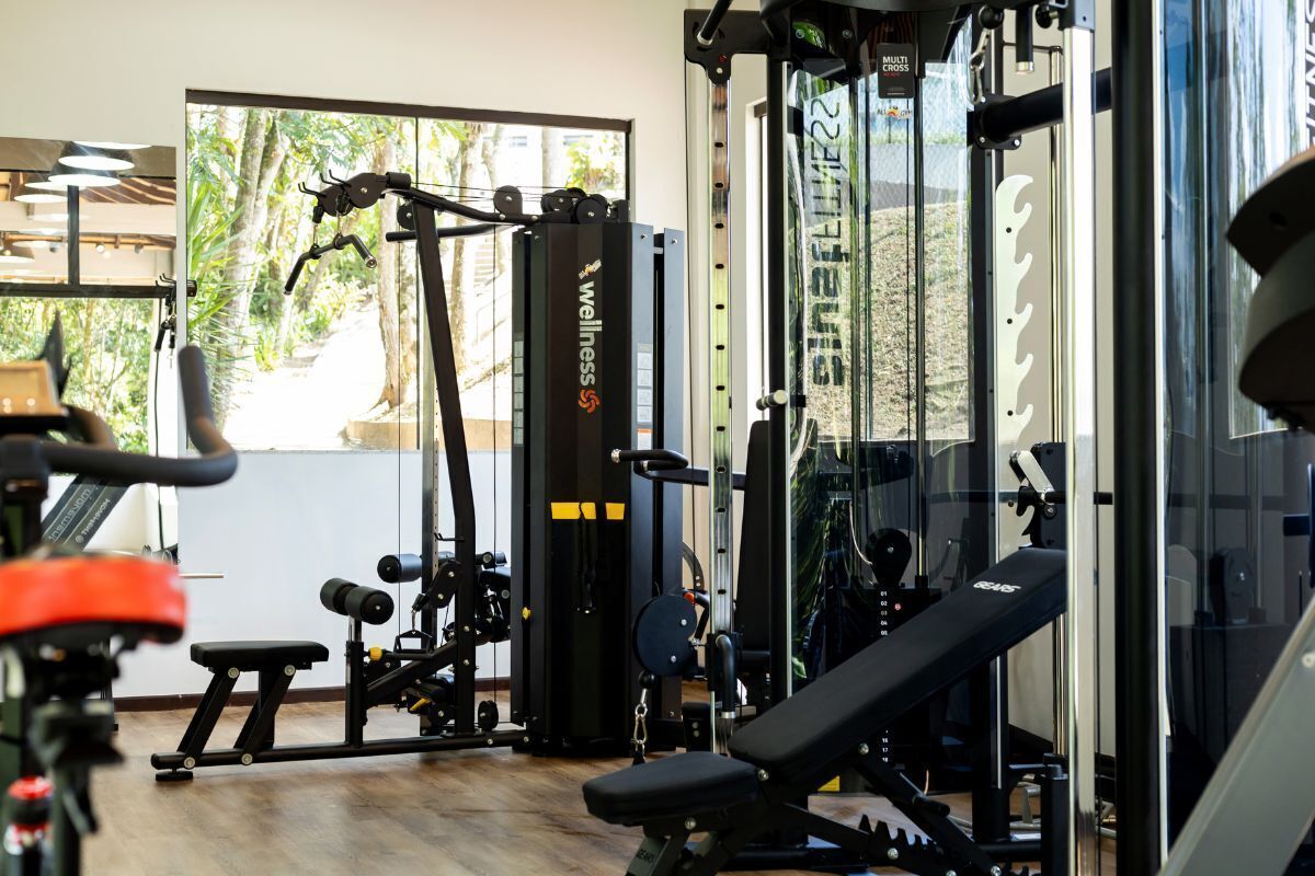 Un gimnasio con diferentes equipos de ejercicio, una banca y un soporte para pesas.