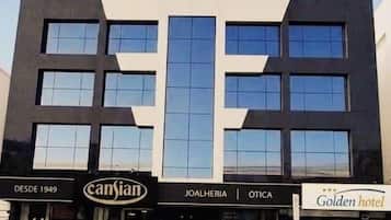Um hotel moderno com vários andares, entrada destacada e placas com 'cansian' e 'Golden hotel'.