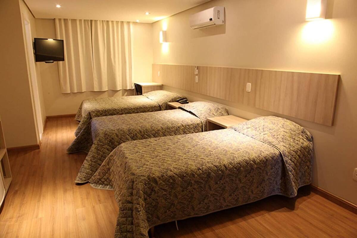 A hotel room with two single beds, a flat-screen TV mounted on the wall, and a wooden headboard.