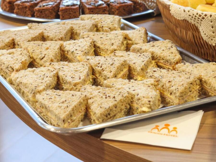 A tray of square-shaped, textured food items on a metal tray, with a wicker basket and a napkin with a logo in the background.