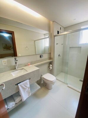A modern bathroom with a sink, toilet, and glass-enclosed shower. - Diaudi Hotel (Sao Jose)