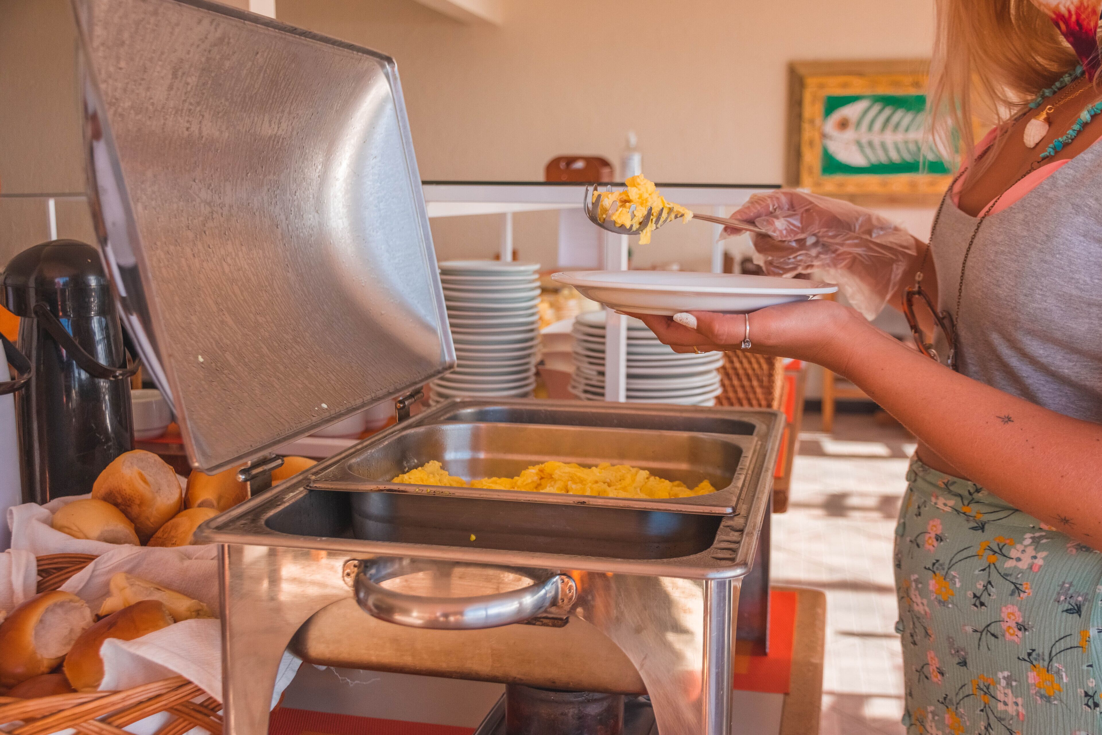 Una mesa de buffet con plancha, platos y una cesta de pan.