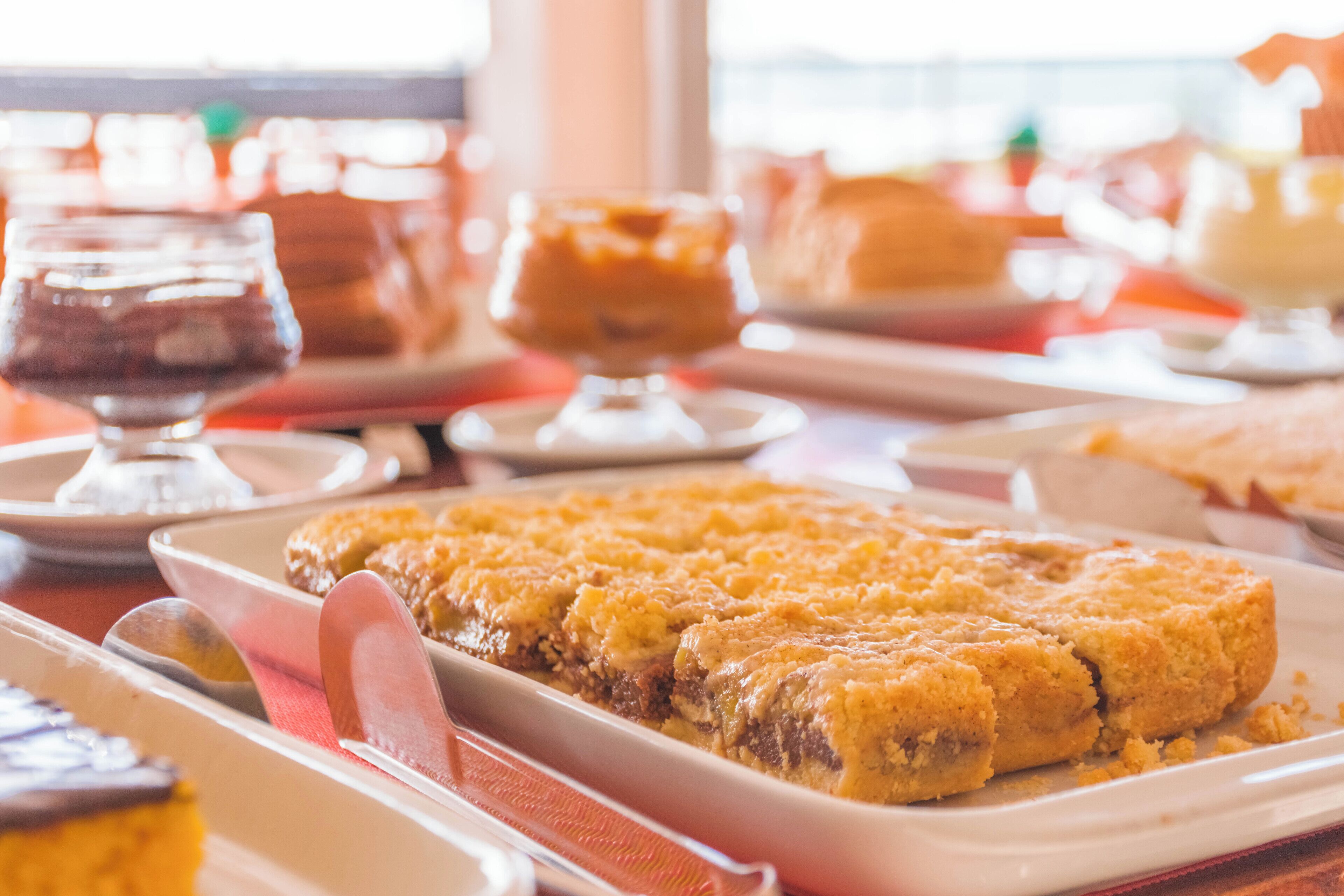 Une table à manger avec différents plats, notamment un gratin de pain de maïs et un dessert servi dans un verre.