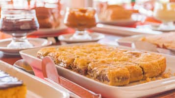 Une table à manger avec différents plats, notamment un gratin de pain de maïs et un dessert servi dans un verre.