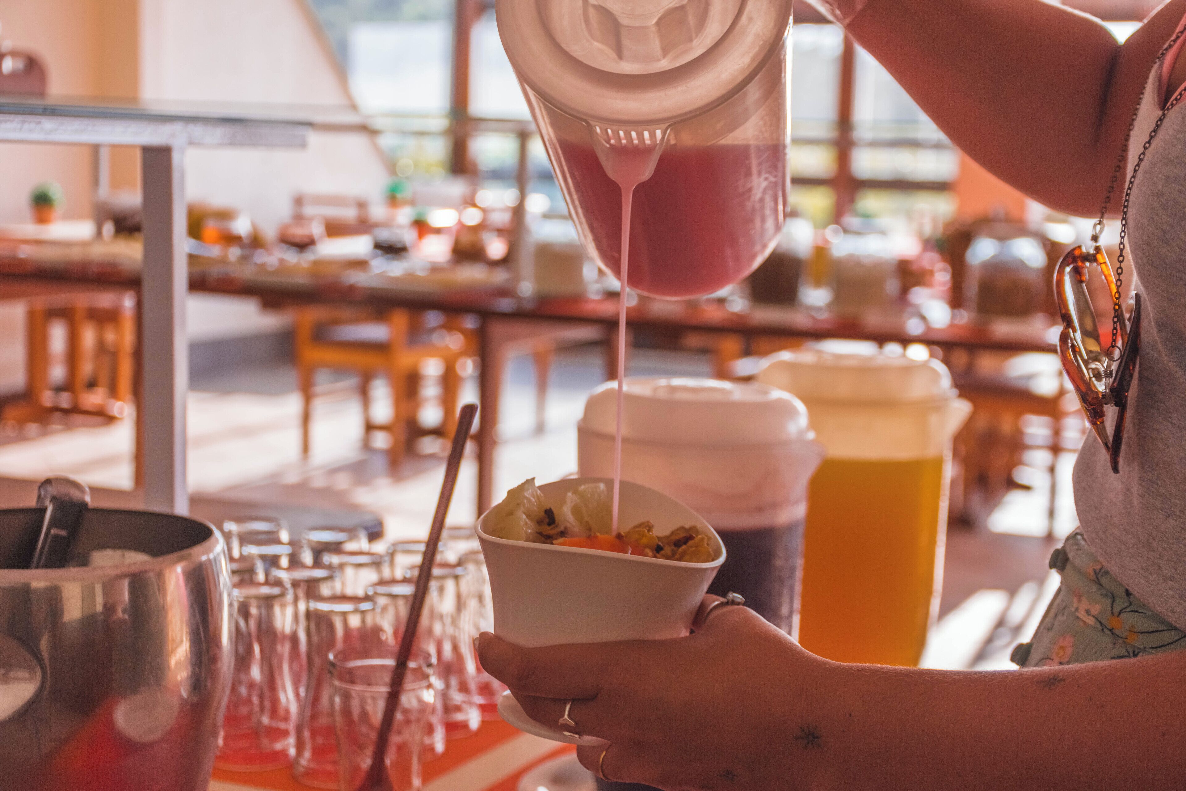 A person pouring a pink liquid into a bowl of food.