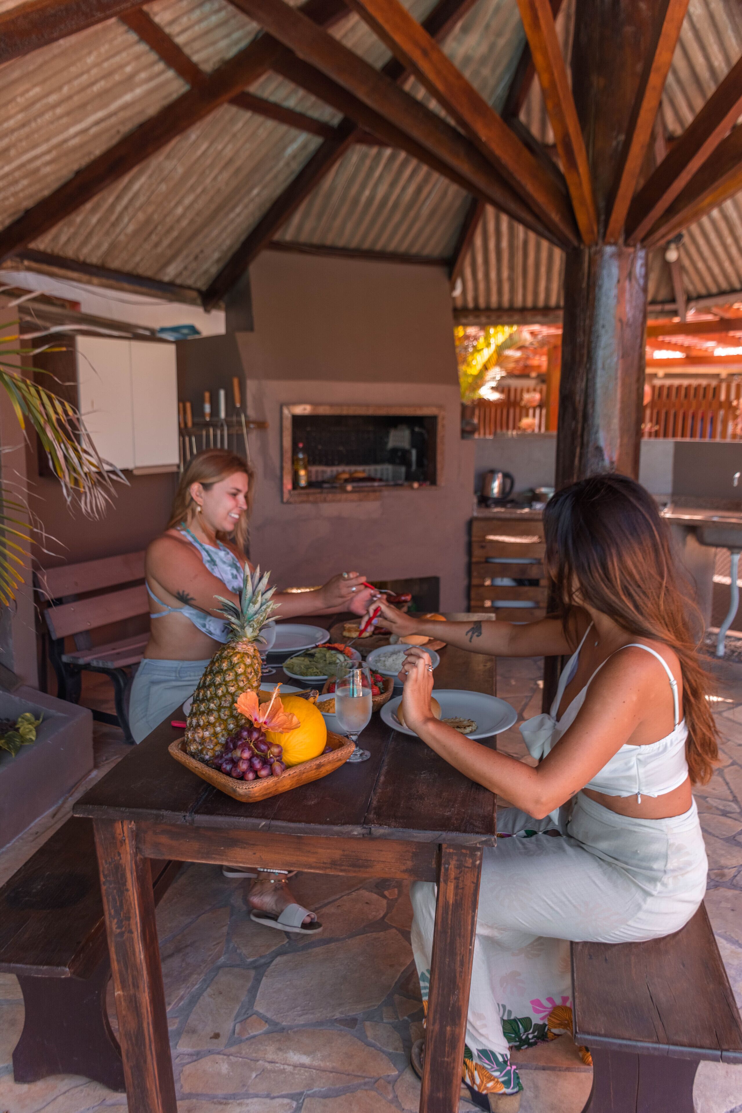 Une table en bois sur laquelle on voit un ananas, des raisins et un saladier rempli de fruits.