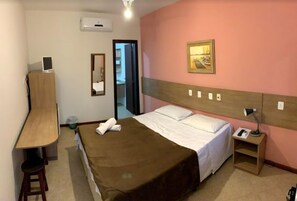Une chambre d’hôtel comprenant un lit, un bureau, une chaise, une table de chevet avec une lampe et un tableau au mur.