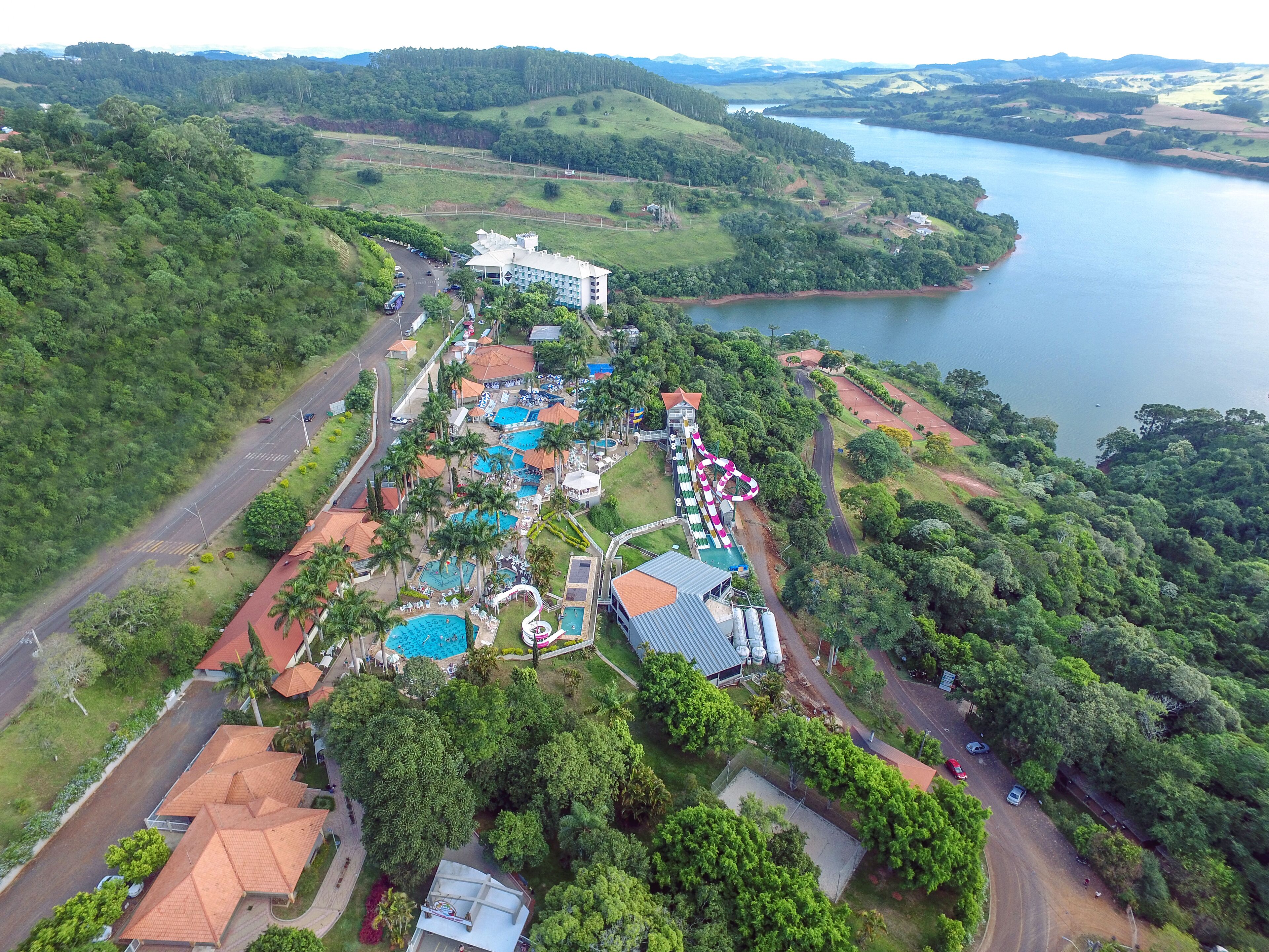 An aerial view of a resort with multiple swimming pools, a water slide, and a large building with a red roof.