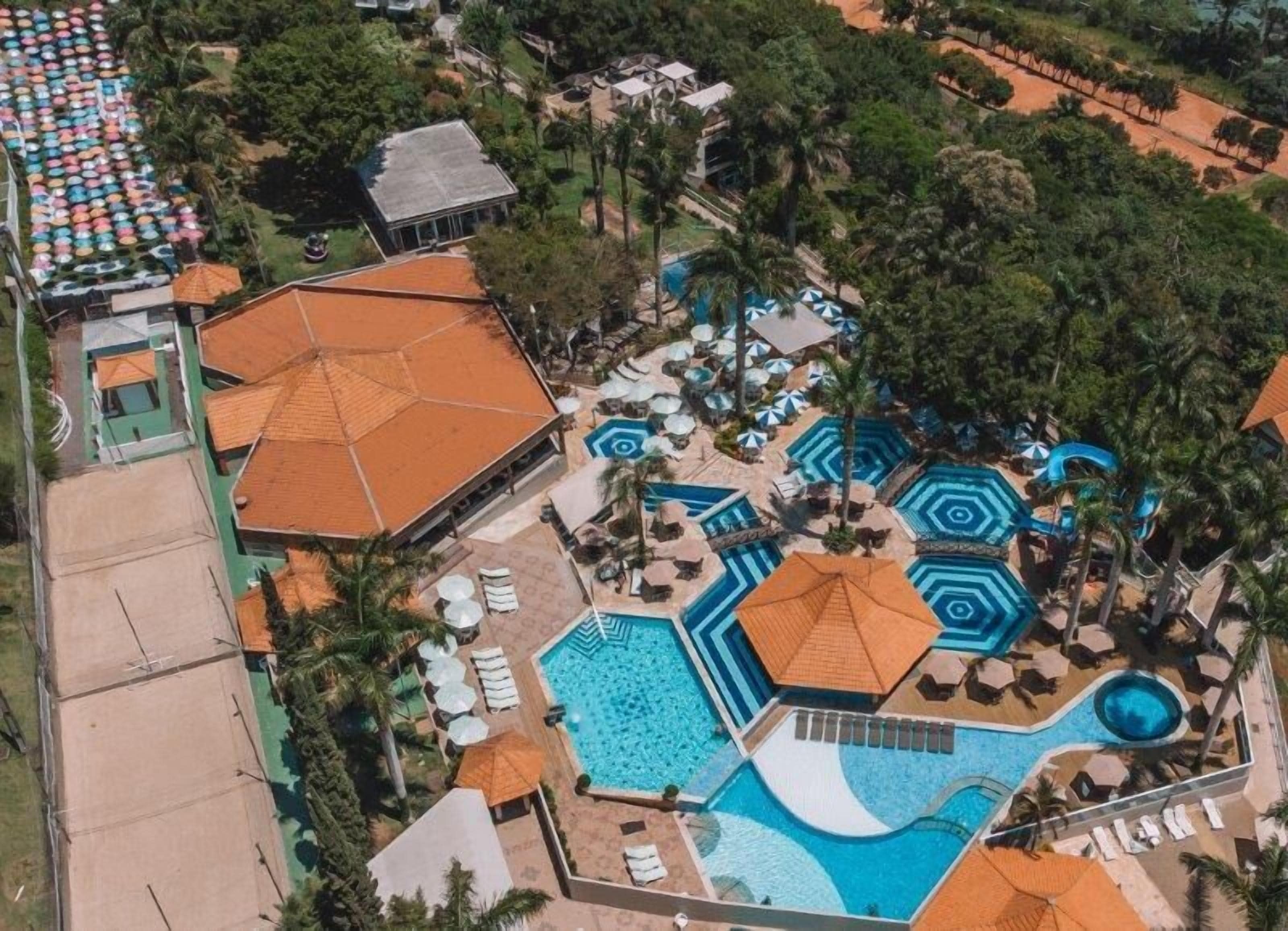 Vue aérienne d’un complexe hôtelier doté de plusieurs piscines, d’espaces de détente et de diverses constructions abritées.