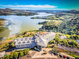 Um hotel com design arquitetônico moderno, situado perto de um lago e colinas ao redor.